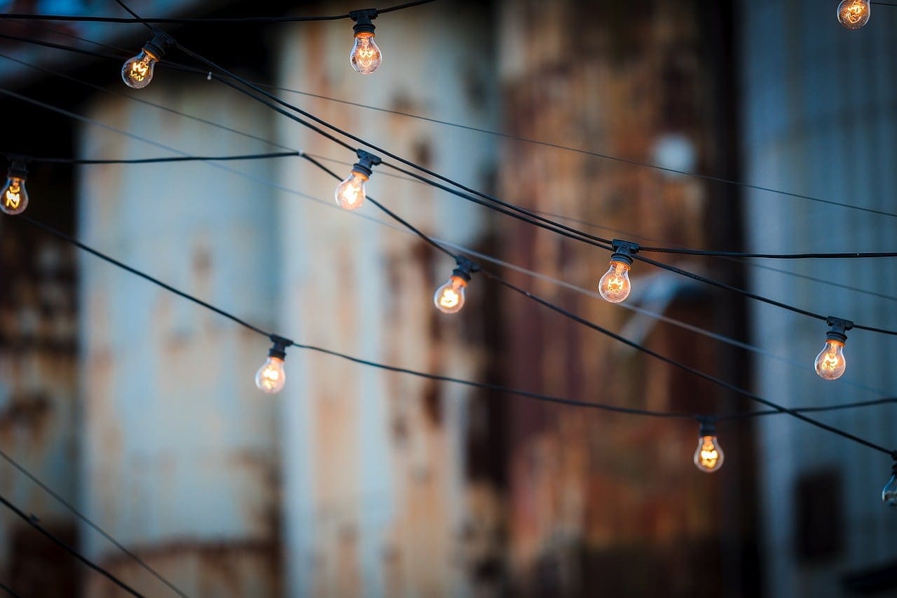 String lights with glowing bulbs crisscross against a blurred, dark background.