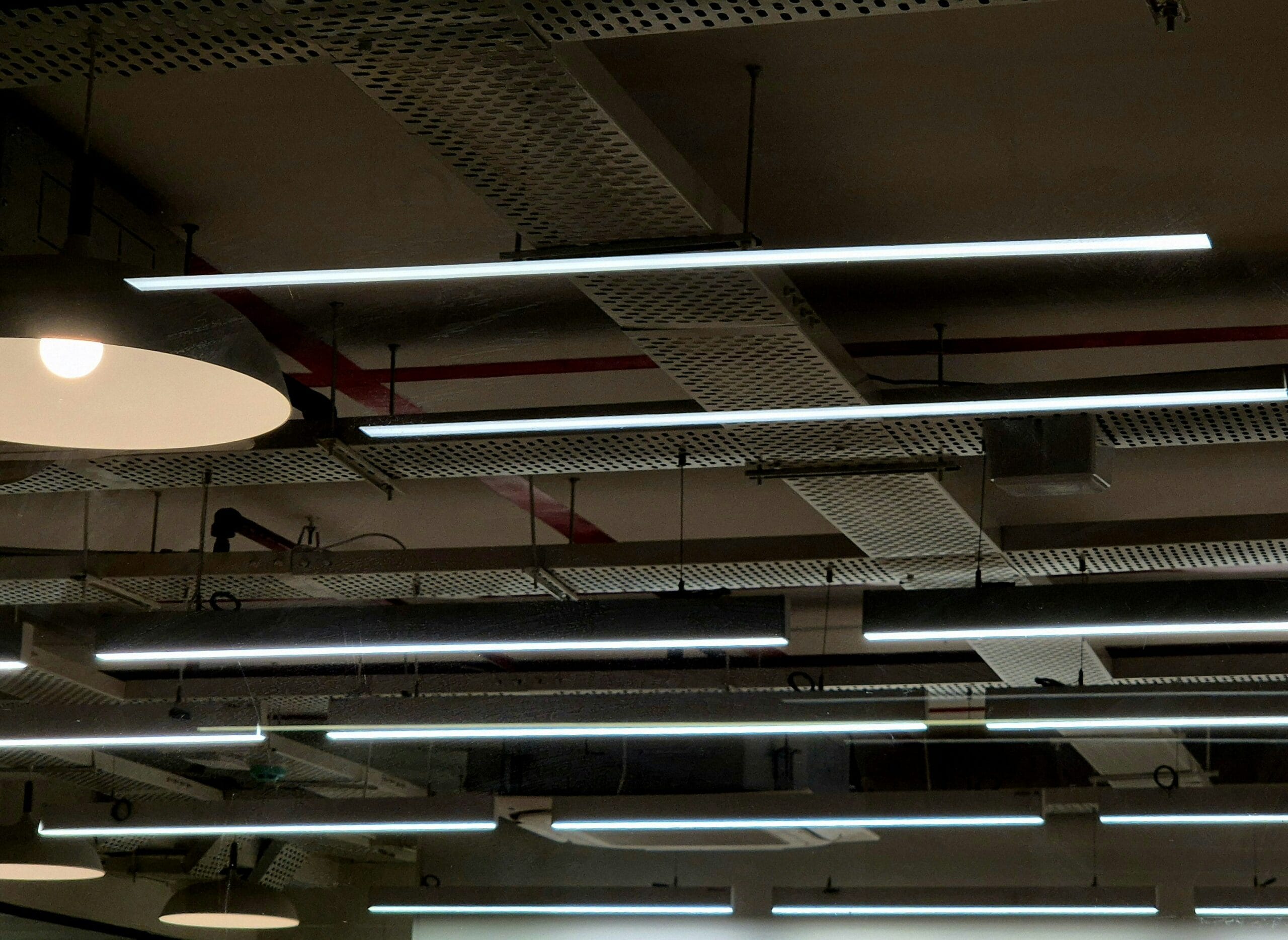 Modern LED linear lights illuminating a commercial workspace ceiling
